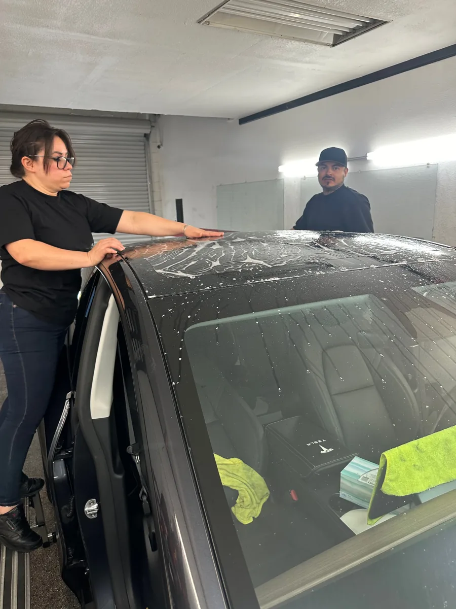 Film being positioned on vehicle glass inside the shop