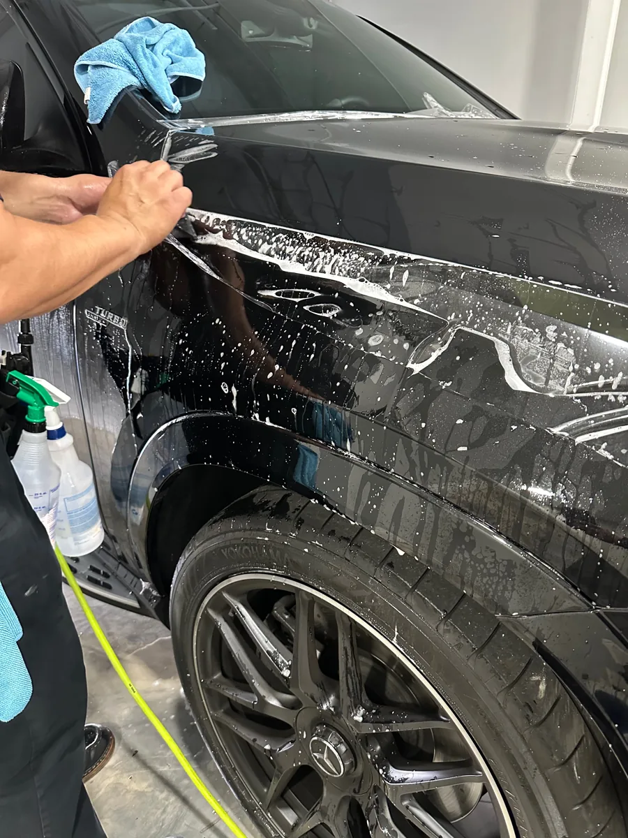 Clear protective film being fitted to a vehicle fender